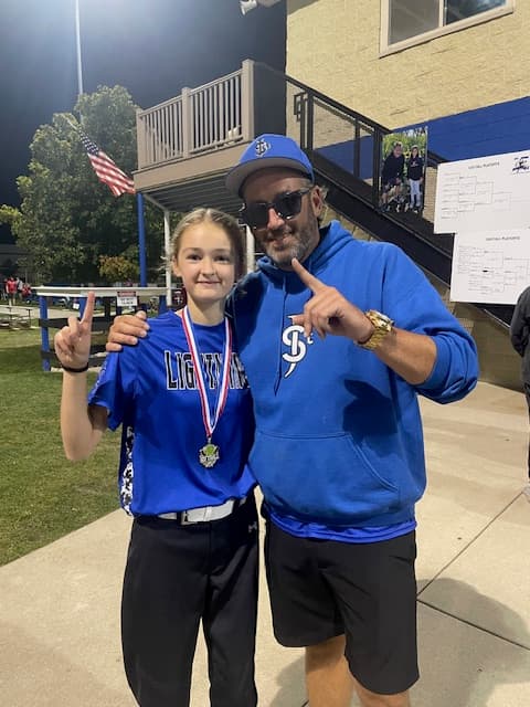 Coach Mo celebrating with a young softball athlete after a game