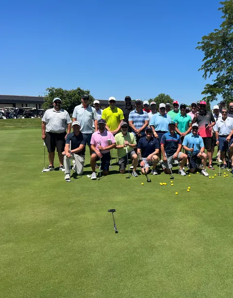 The full field gathered on the green at the MOments Golf Outing