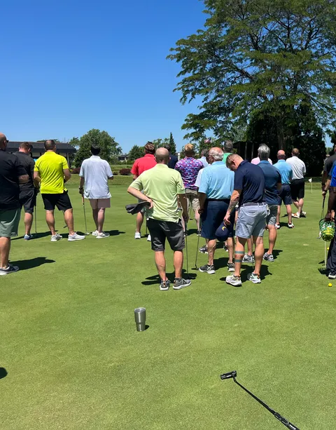 The field gathered on the practice green before the round
