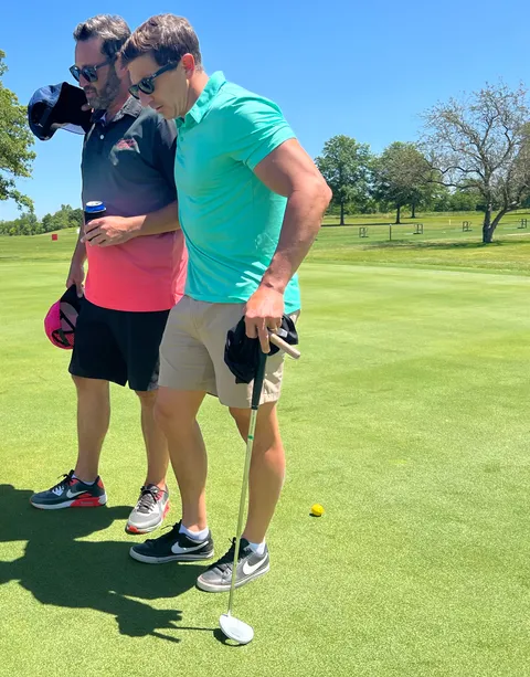 Golfers reading a putt together on the green