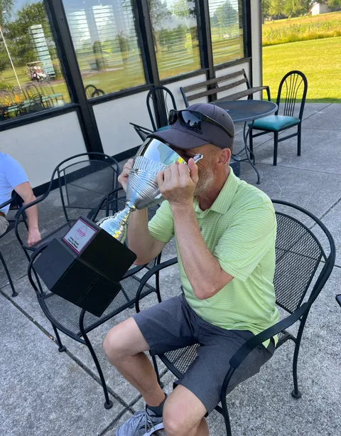 A winner taking a victory drink from the trophy