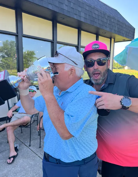 Two golfers celebrating with the outing trophy