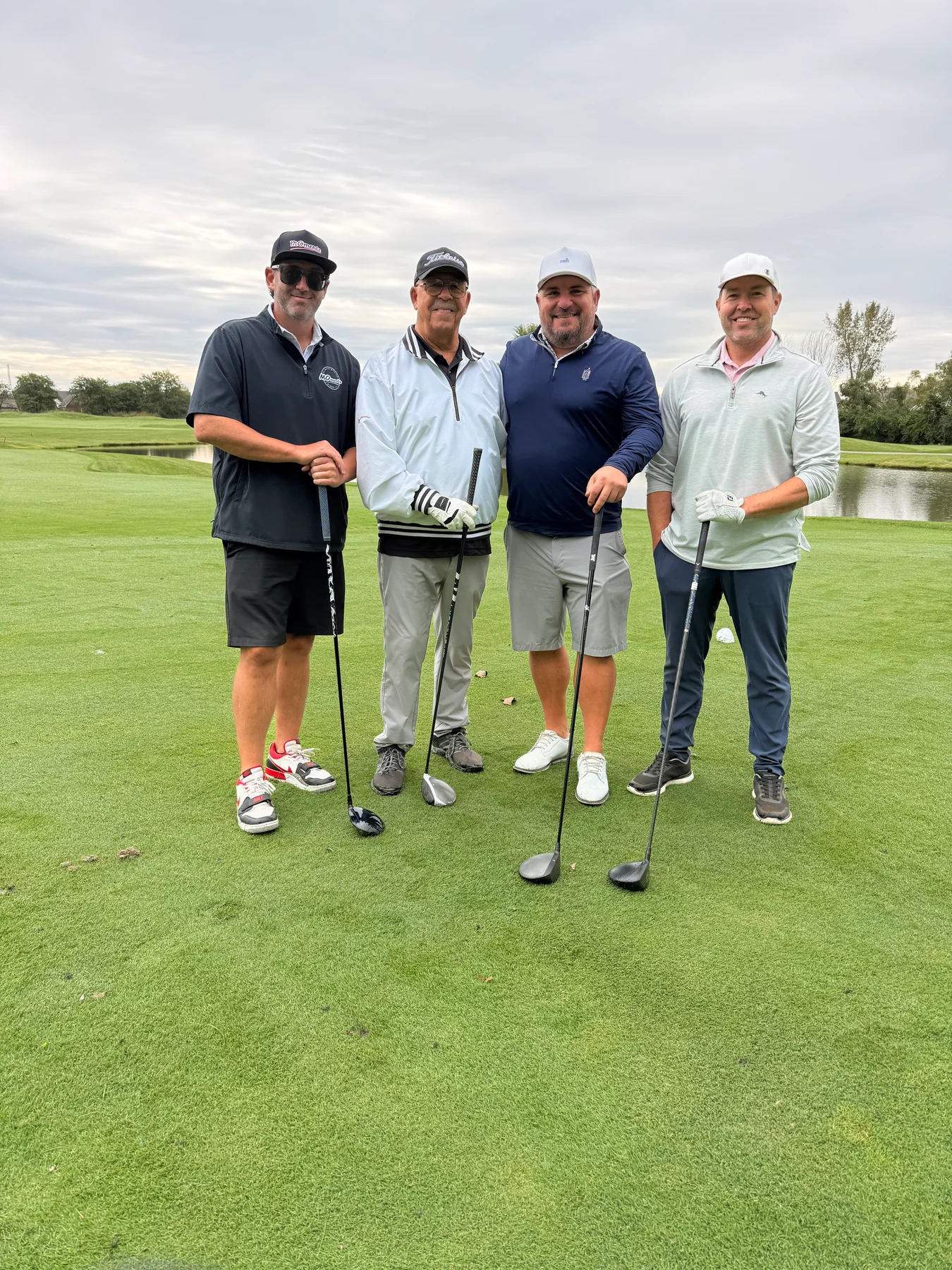 Four golfers pose together on the course in MOments gear