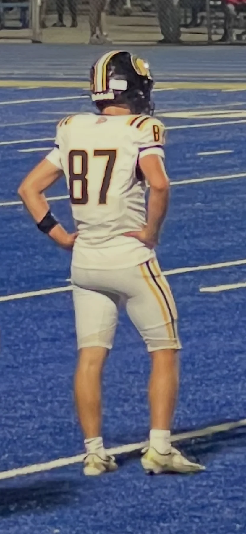A football athlete wearing number 87 watches the action from a blue field