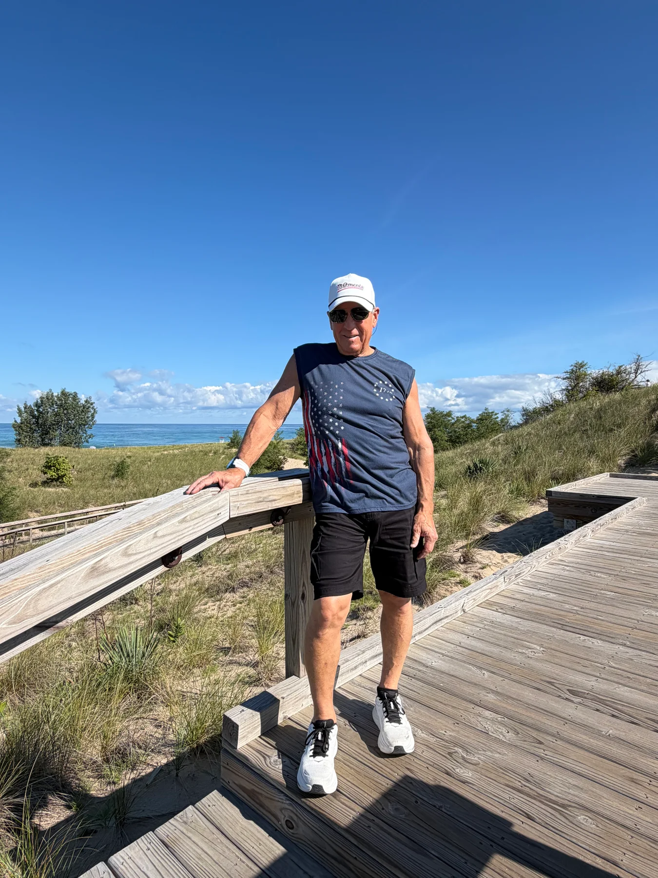 A supporter wears a white MOments cap on a lakeside boardwalk